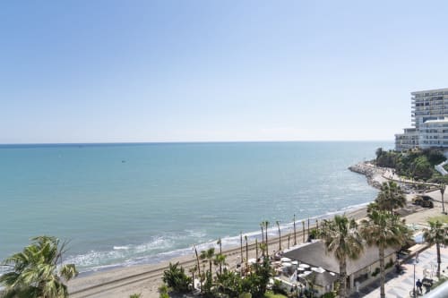 Vistas de mar turquesa y playa arenosa desde el apartamento premium ROCA Beach Torremolinos con palmeras y frente marítimo moderno
