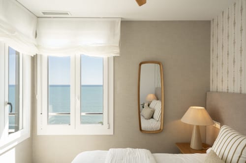 Dormitorio de apartamento frente al mar con vistas al océano, espejo de madera, mobiliario moderno en Torremolinos