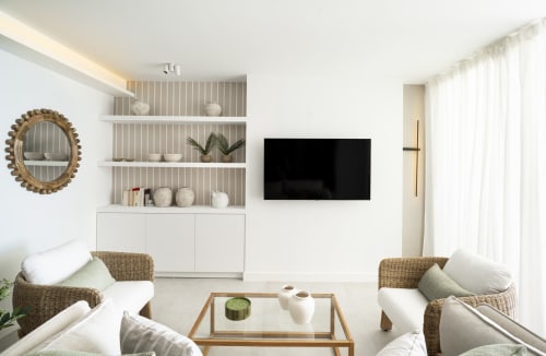 Moderno salón con sillas tejidas, TV empotrada y estanterías en el apartamento premium ROCA Beach Torremolinos, España
