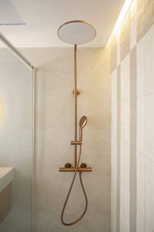 Sistema moderno de ducha de lluvia en bronce en baño con azulejos beige del apartamento Premium ROCA Beach Torremolinos en España