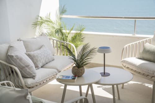 Terraza lounge frente al mar en ROCA Beach Torremolinos con vistas al océano, mobiliario blanco, palmeras en macetas y mesas redondas