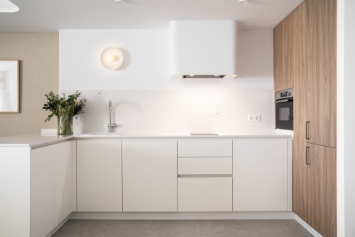 Cocina moderna blanca con detalles de madera en apartamento Premium ROCA Beach Torremolinos, equipada con electrodomésticos de acero inoxidable