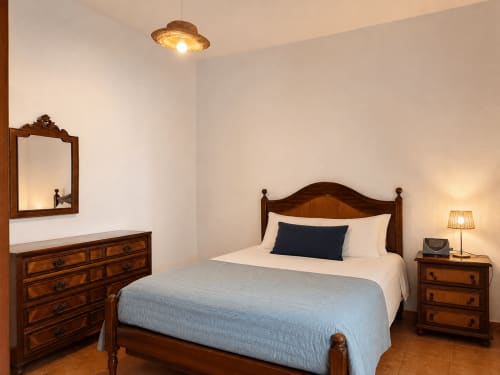 Quarto da Villas Simone com móveis em madeira, roupa de cama azul e iluminação aconchegante