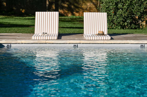 Two striped lounge chairs by a crystal-clear pool at La Maison & l'Orangerie in Saint-Jean-des-Vignes