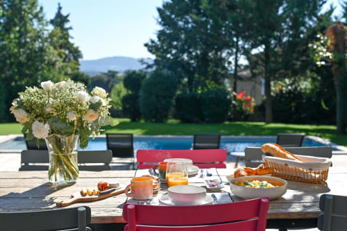 Elegant poolside breakfast setup at La Maison & l'Orangerie with fresh pastries, flowers, and mountain views in