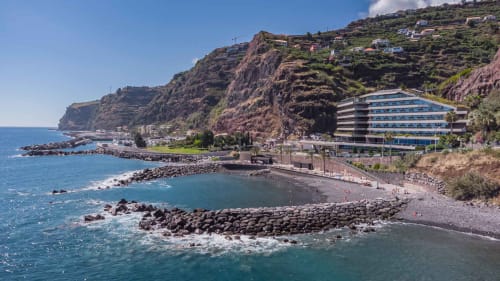 Hotel frente ao mar BHF Residences em falésias dramaticamente posicionadas no Arco da Calheta, Portugal, com enseada rochosa e oceano azul