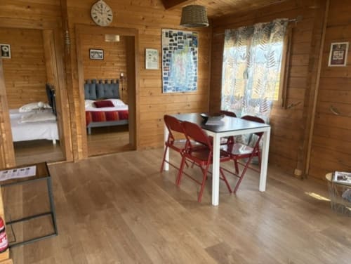 Espace de vie du Chalet Golo avec table à manger, chaises rouges, intérieurs en bois, vue sur la chambre aux Chalets de Lozzi, Lozzi FR
