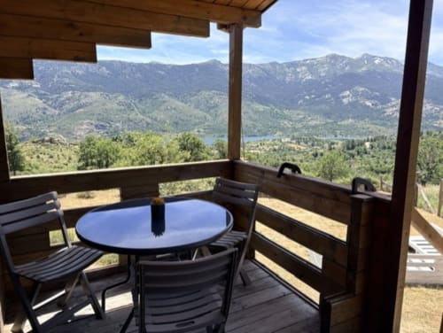 Terrasse en bois avec table et chaises vue sur le lac Lozzi et les montagnes, villa Les Chalets de Lozzi