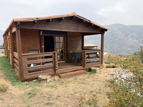 Chalet en bois avec véranda enveloppante à Lozzi, Corse, entouré de montagnes et de jardins