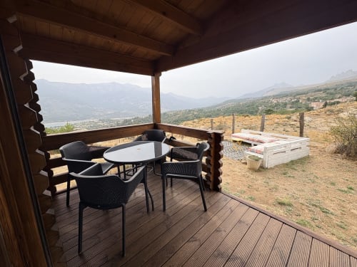 Terrasse couverte du Chalet Paglia Orba avec table à dîner, chaises noires, vue sur les montagnes et le lac à Lozzi
