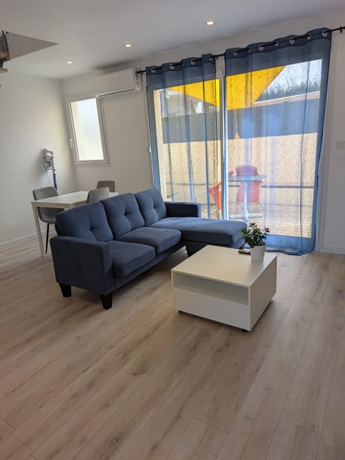 Salon moderne avec canapé bleu marine et table basse blanche donnant sur la piscine chauffée de la Résidence des dunes, Landéda