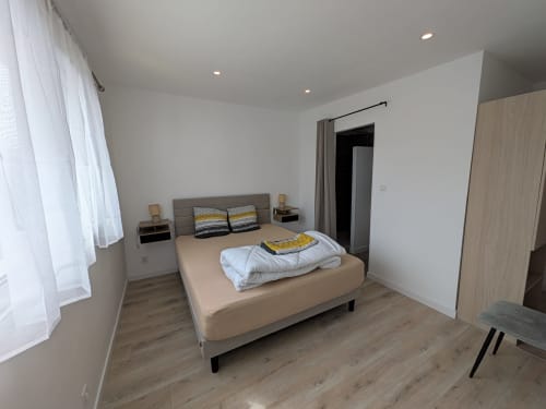 Chambre lumineuse à la Résidence des dunes à Landéda avec lit beige, tête de lit grise, parquet et équipements modernes