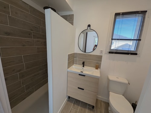 Salle de bains moderne du gîte Résidence des dunes à Landéda avec vasque, miroir, toilettes et douche à l'italienne