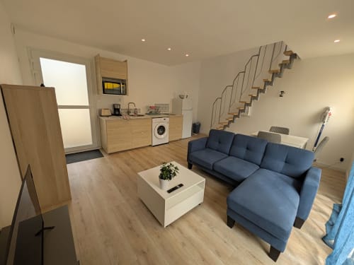 Intérieur moderne de la résidence des dunes à Landéda : canapé bleu, cuisine et escalier en bois