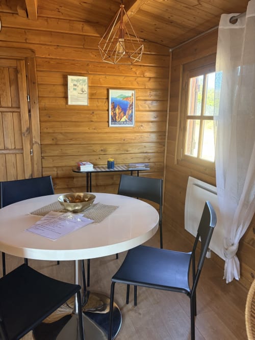 Salle à manger rustique de chalet avec table ronde blanche, chaises noires, luminaire géométrique et œuvres encadrées aux Trois