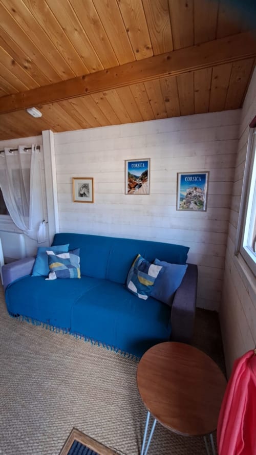 Canapé bleu avec coussins dans un salon douillet de chalet en bois, décoration corse et vue sur les montagnes