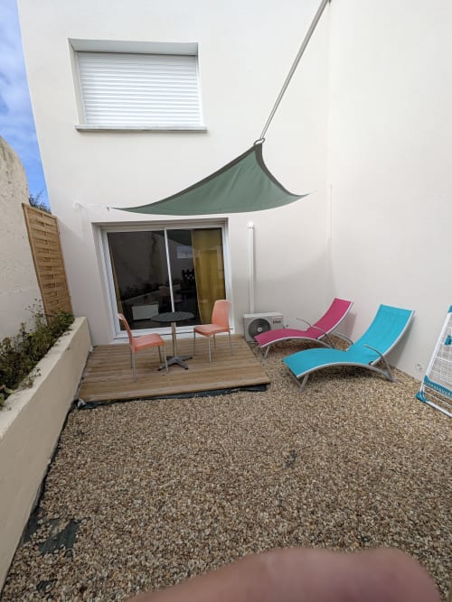 Terrasse de cottage à la Résidence des dunes avec voile d'ombrage verte, transats colorés et patio en graviers à Landéda