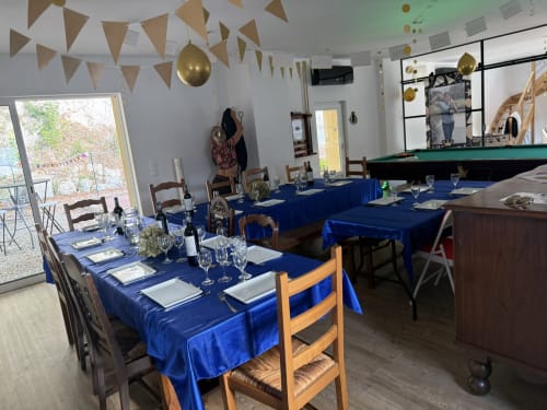 Élégante salle à manger des Gîtes de Flaubert avec tables dressées de bleu, guirlandes dorées et billard.