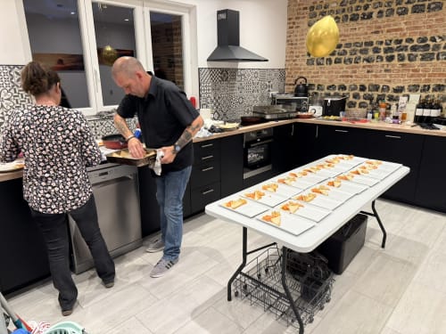 Chef préparant des entrées dans la cuisine moderne des Gites De Flaubert, Morville le Héron, avec des plats dressés sur table.
