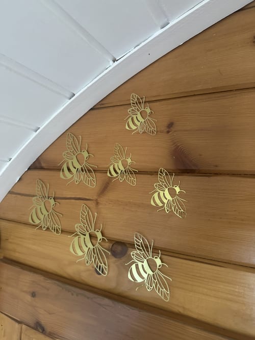 Decorative golden bee stencils adorning wooden ceiling beams in Bumblebee Pod at Acorns Luxury Glamping, Holywell