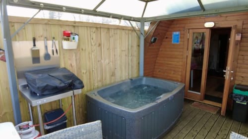 Hot tub and outdoor deck area at Acorns Luxury Glamping Bumblebee Pod in Holywell with wood cabin entrance