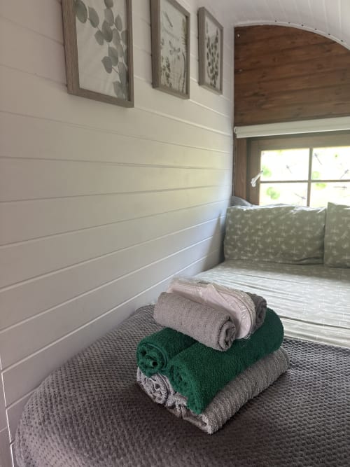 Rolled towels in green and beige stacked on carpet in Dragonfly Pod bedroom at Acorns Luxury Glamping, Holywell