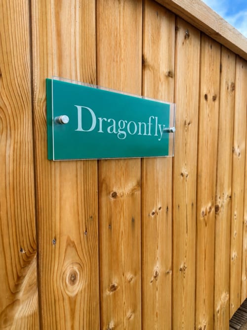 Dragonfly Pod entrance sign on wooden cladding at Acorns Luxury Glamping, Holywell