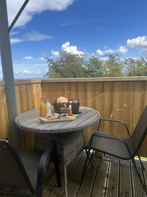 Outdoor balcony at Acorns Luxury Glamping with round table, breakfast spread, and garden views in Holywell