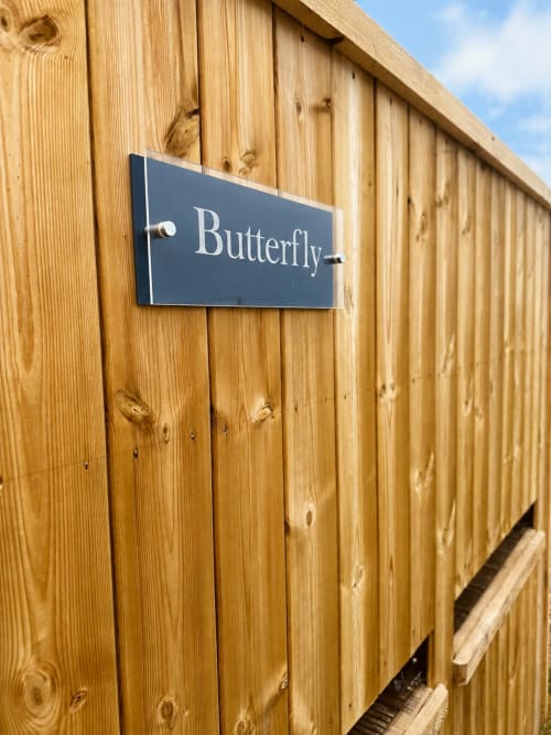 Butterfly Pod nameplate on wooden exterior wall at Acorns Luxury Glamping in Holywell