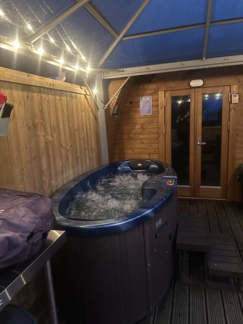 Outdoor hot tub with bubbling water on a wooden deck at Butterfly Pod, Acorns Luxury Glamping, Holywell, at dusk