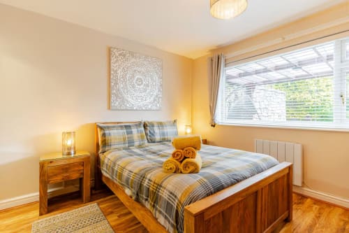 Cozy bedroom at Acorns Luxury Glamping in Holywell with wooden bed, plaid bedding, garden views, and warm lighting