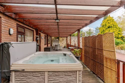 Hot tub on covered deck at Acorns Luxury Glamping, Holywell with garden views and brick privacy fence