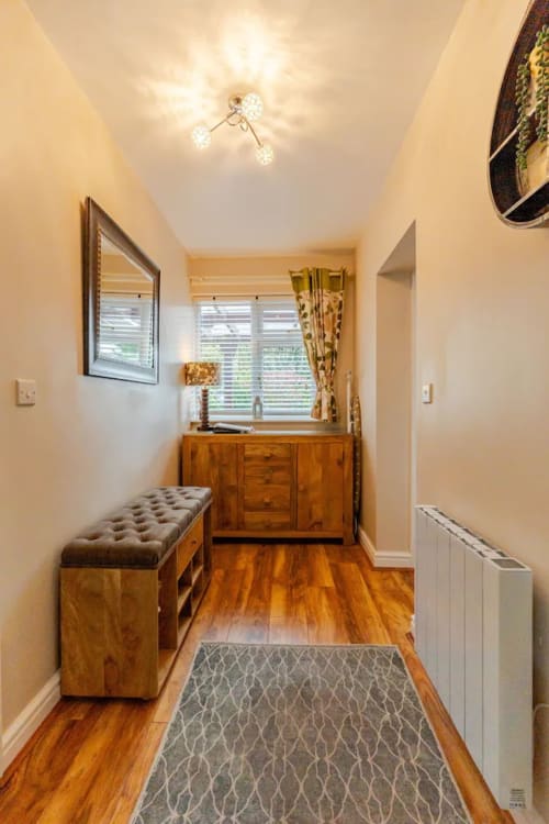 Bright hallway in Acorns Luxury Glamping apartment with wooden dresser, storage bench, and garden view windows