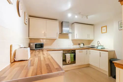 Modern kitchen with cream cabinets, wooden countertops, and stainless steel appliances at Acorns Luxury Glamping in Holywell
