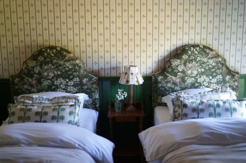 Lits jumeaux aux têtes de lit florales dans une chambre de villa en Provence à la Ferme de La Roquerie