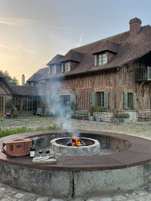 Foyer avec vin et panier de pique-nique surplombant la bastide La Roquerie, architecture rustique au crépuscule