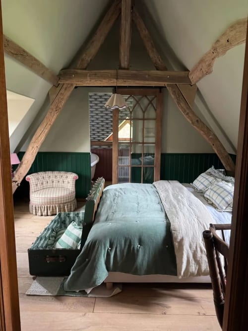 Chambre rustique avec poutres apparentes, lambris vert, lit à baldaquin et mobilier élégant à La Roquerie