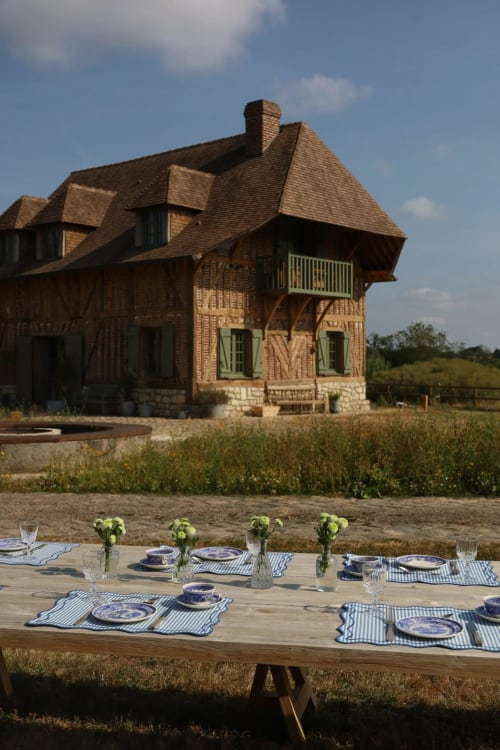 Aménagement de repas en plein air à la Ferme La Roquerie avec manoir en brique et paysage de la campagne française