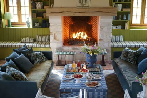 Élégant salon de villa à la campagne française avec cheminée, banquette verte intégrée et salle à manger formelle à La Roquerie
