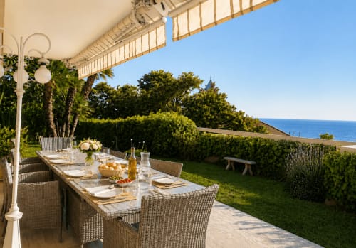 Terrasse de salle à manger en bord de mer à Cannes, table dressée, vue sur la mer et jardin méditerranéen de l'appartement Le Saint Georges