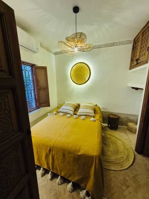 Chambre Stella Suite au Riad Casa Angelo à Marrakech avec literie jaune et luminaire suspendu en tissage