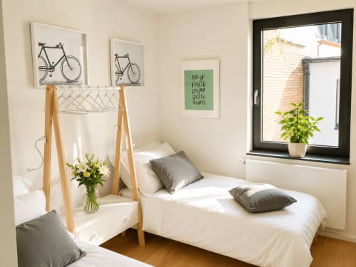 Chambre lumineuse dans un appartement luxembourgeois avec lit blanc, portant bois, art cycliste, plantes en pot et vue sur la ville