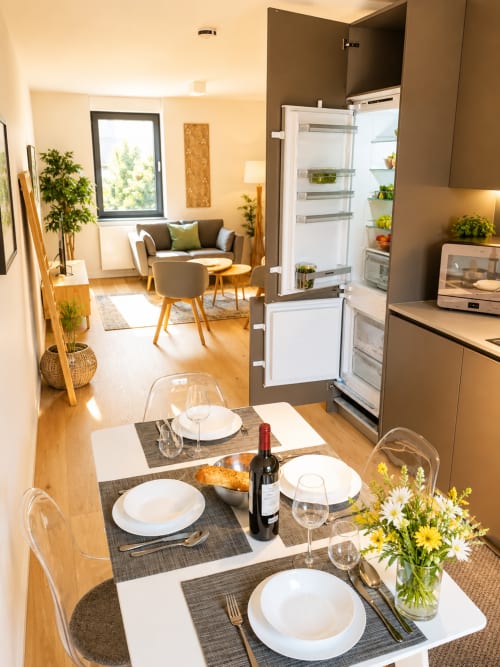 Salle à manger d'un appartement moderne avec table dressée, cuisine ouverte et séjour au Luxembourg