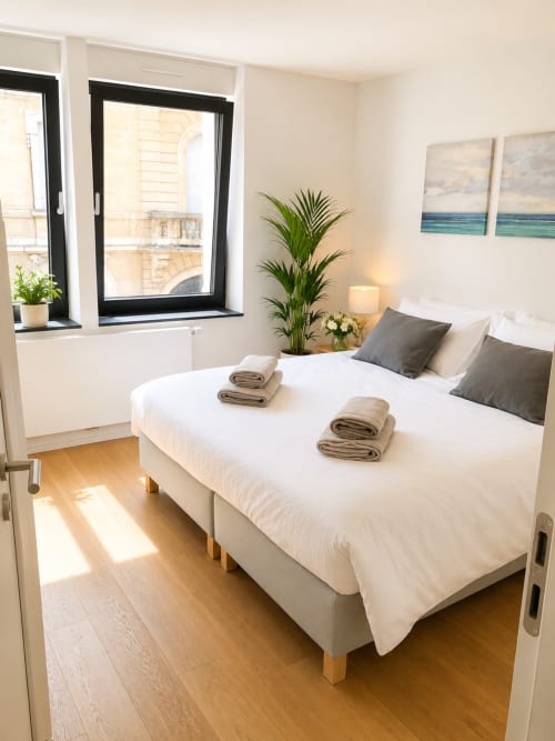 Chambre moderne à Mattbnblux1 à Luxembourg avec lits jumeaux, vue sur la ville, plante en pot et parquet