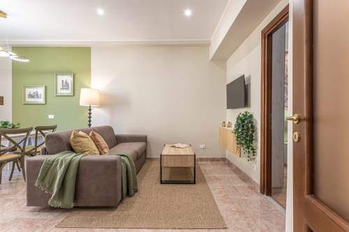Boutique familiare a Roma vicino al Colosseo con soggiorno moderno, divano marrone e parete accent verde