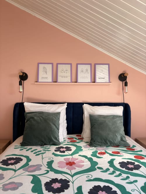 Cozy villa bedroom at La Villa Maraloupia with coral wall, navy headboard, floral bedding, and framed artwork on shelf