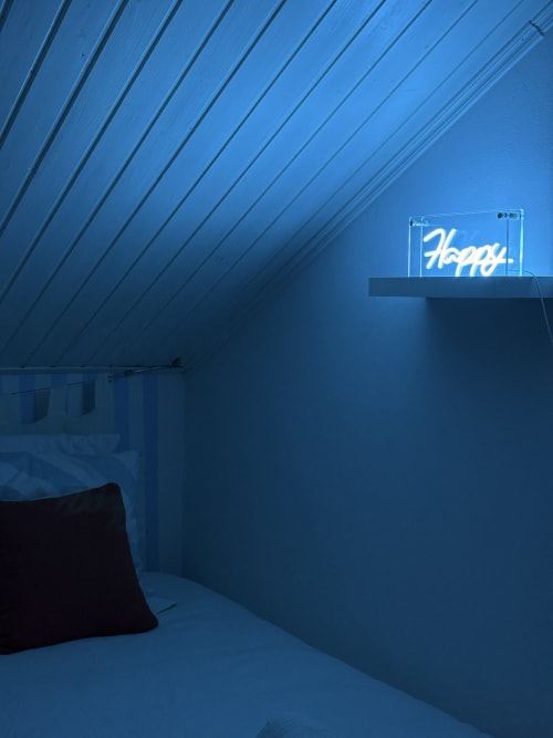 Modern attic bedroom at La Villa Maraloupia with blue neon 'Happy' sign and sloped ceiling, Les Avirons Reunion