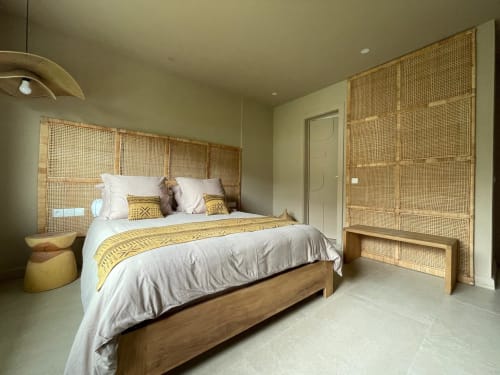 Chambre Nomads Togo avec tête de lit en rotin tressé, lit en bois, literie blanche et vue sur le jardin à Lomé