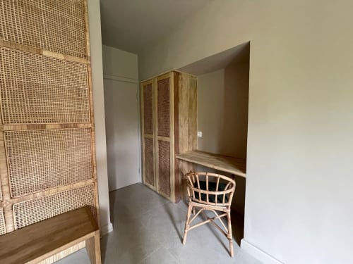 Chambre Nomads Togo avec armoire tissée, fauteuil en rotin et équipements modernes à Lomé