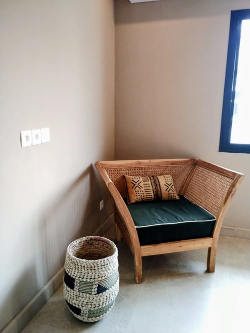 Coin douillet avec fauteuil en rotin, coussin vert, coussins décoratifs et panier tressé chez Nomads Togo